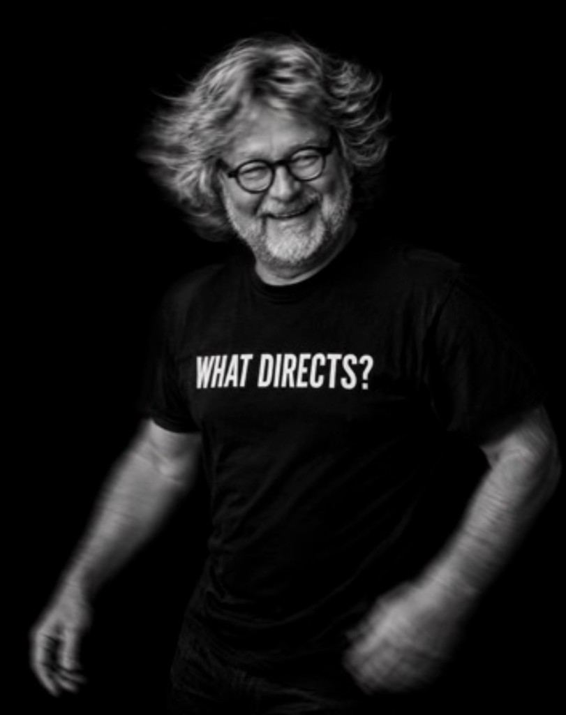 Steffen Rolla im Schwarz-Weiß-Porträt, schwarzes T-Shirt mit der Aufschrift WHAT DIRECTS?